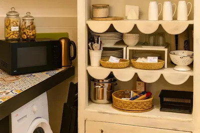 a kitchen with a microwave and a shelf with dishes at AthaHome Deluxe in Palermo
