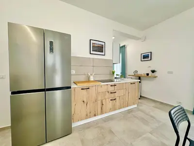 a kitchen with a stainless steel refrigerator and wooden cabinets at Sea Life Giulia, spiaggia a 200 mt in Alcamo Marina