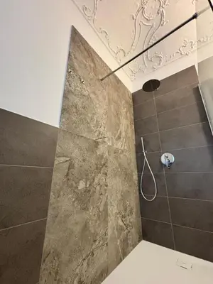 a bathroom with a shower with a stone wall at Historic Palazzo - Apartments & Rooms with Private Bathroom in Palermo