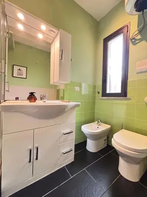 a green bathroom with a sink and a toilet at Maison N 16 in Palermo
