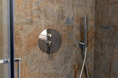 a shower with a mirror on a stone wall at Le Case del Massimo in centrocittà in Palermo