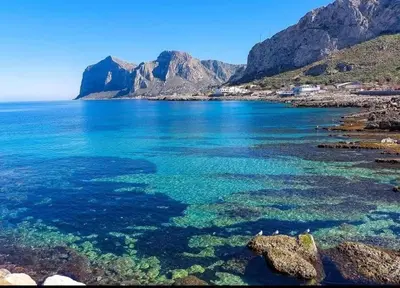a large body of water with mountains in the background at La rosa dei venti in Isola delle Femmine