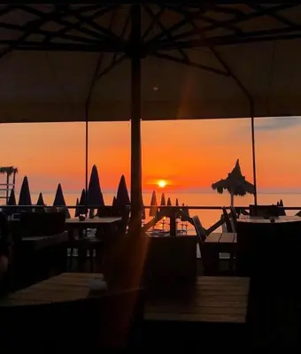 a sunset on the beach with tables and umbrellas at La rosa dei venti in Isola delle Femmine