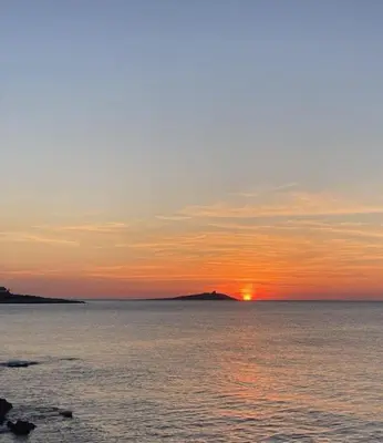 a sunset over the water with a island in the distance at La rosa dei venti in Isola delle Femmine