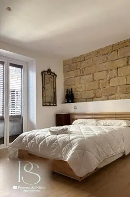 a bedroom with a large bed and a brick wall at Palermo Sunset in Palermo