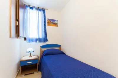 a bedroom with a blue bed and a window at Casa vacanze Giusi in Castellammare del Golfo