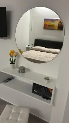 a bedroom with a mirror on a white wall at La Casetta di Sa Lu in Capaci