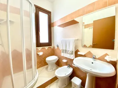 a kitchen and dining room with a table and a red couch at Residence Piana, San Vito Lo Capo in San Vito lo Capo