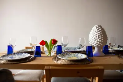a wooden table with blue and white plates and wine glasses at Vela House charming front of sea in Palermo