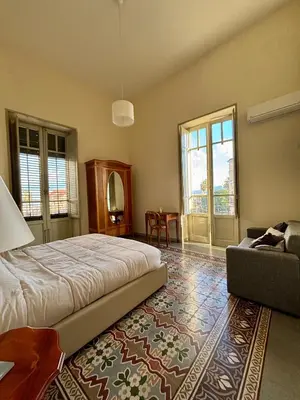 a bedroom with a bed and a couch and windows at La Casa di Alan in Palermo