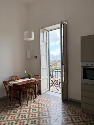a kitchen and dining room with a table and a balcony at La Casa di Alan in Palermo