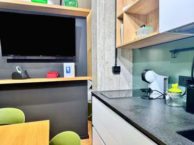 a kitchen with a tv and a counter with green chairs at Plaza Suite in Palermo