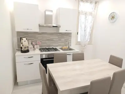 a kitchen with white cabinets and a table with chairs at La casa di gabry in Palermo