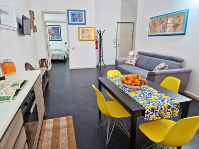 a kitchen and living room with a table and yellow chairs at Cattedrale - Maiolica Brugnò in Palermo
