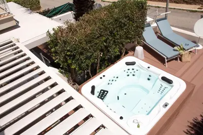 a hot tub sitting on a deck next to a chair at Anemos Apartment - Villa Luna in Macari