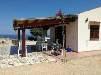 a house with a patio and a table and chairs at Casetta Rosina in Scopello