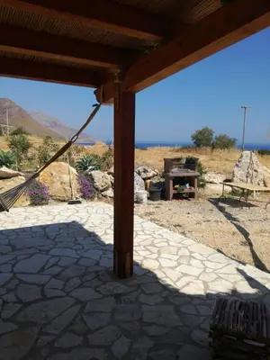 a pavilion with a picnic table and mountains in the background at Casetta Rosina in Scopello