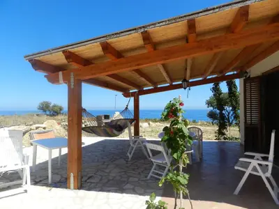 a wooden pergola with a hammock on a patio at Casetta Rosina in Scopello