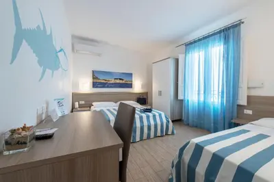 a hotel room with two beds and a desk and a table at La Nicchia in San Vito lo Capo