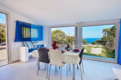 a dining room with a table and a view of the ocean at Villa Pandora in Scopello