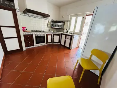 a kitchen with a orange tile floor and yellow chairs at More Holidays Sun in Mondello
