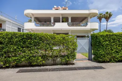 a white building with a gate and some bushes at More Holidays Sun in Mondello
