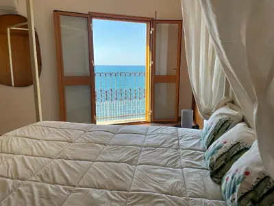 a bedroom with a bed with a view of the ocean at Finestra sul golfo in Balestrate