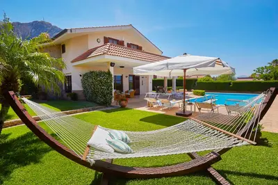 a hammock in front of a house with a pool at Villa Cottone - 5 suite con piscina privata - tra Palermo e Cefalù in Altavilla Milicia