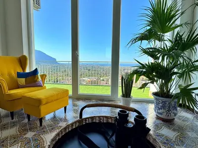 a living room with a yellow chair and large windows at The Best View Sicily Apart in Carini