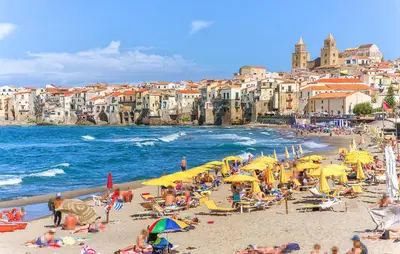 a group of people on a beach with yellow umbrellas at Nice Apartment In Collesano Pa in Lascari