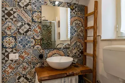 a bathroom with a bowl sink and tiles on the wall at GuestHost - Castrum Lodge - Ballarò Stylish Apartment in Palermo