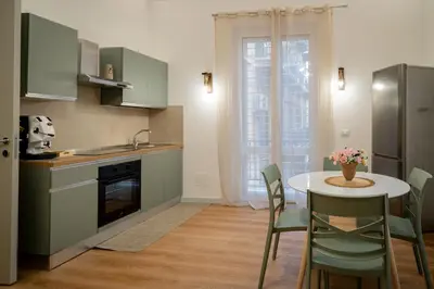 a kitchen with a table and chairs and a kitchen with green cabinets at Palermo Centro Gaale in Palermo
