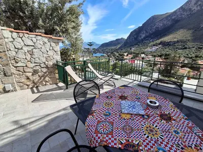 a table with an umbrella on a balcony with mountains at VFH Residence Flavia -Tre Piscine in Santa Flavia