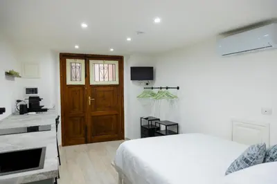 a bedroom with a white bed and a wooden door at Stratuzza Apartments in Palermo