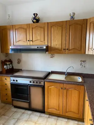 a kitchen with wooden cabinets and a stove and a sink at La Dimora della Maestra in Vita
