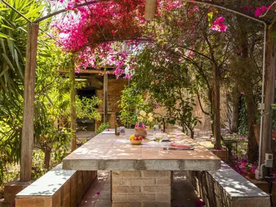 a table in a garden with pink flowers at Apartment Cicladi Leros by Interhome in Santa Flavia