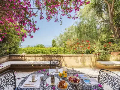 a table with food on a patio with flowers at Apartment Cicladi Anafi by Interhome in Santa Flavia