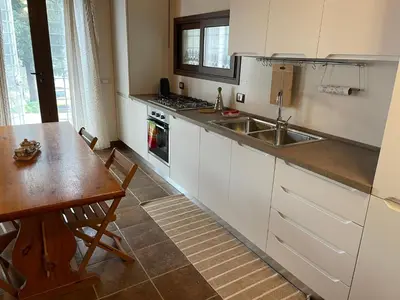 a kitchen with white cabinets and a table and a sink at Lally in the Sky moderno monovano panoramico ed accessoriato in Scopello