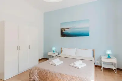 a white bedroom with a bed and two tables at Archi in Balestrate