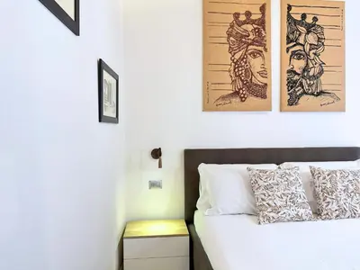 a bedroom with a bed with two pictures on the wall at Helena Apartments - Secondo Canto in Palermo