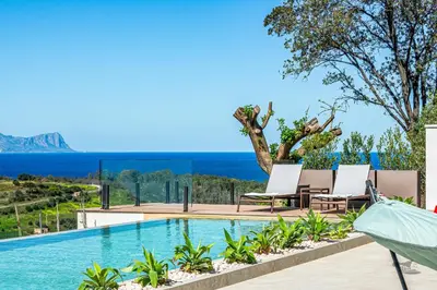 a view of a swimming pool with two chairs and the ocean at Villa Castello in Balestrate