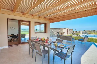 a dining room with a table and chairs on a patio at Villa Al-Kurum in Alcamo Marina