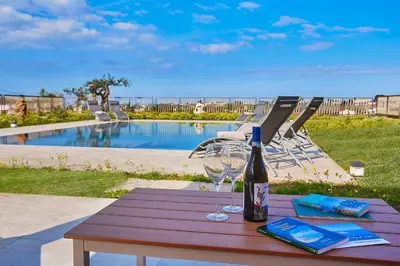 a wooden table with a bottle of wine and a glass at Villa Al-Kurum in Alcamo Marina