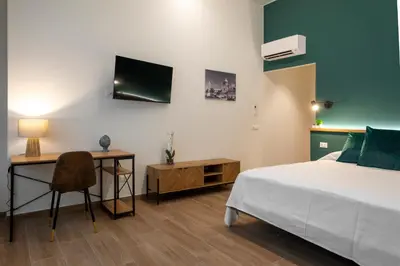 a bedroom with a bed and a desk and a tv at Marina Rooms - Guesthouse in Palermo