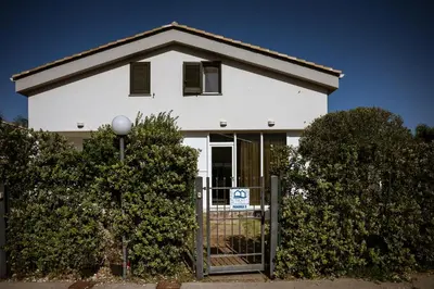 a white house with a for sale sign in front of it at Residence Salinelle Beach Villa Panarea in Lascari