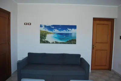 a living room with a couch and a painting on the wall at Casa Punta Barcarello, Sferracavallo fronte mare e tramonti da sogno, a due passi dalla splendida spiaggia di Mondello in Palermo