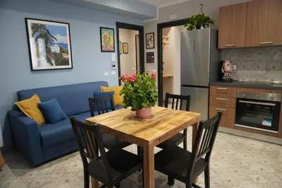 a kitchen and living room with a table and a blue couch at Maria's Home in Altavilla Milicia