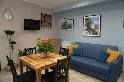 a living room with a blue couch and a table at Maria's Home in Altavilla Milicia