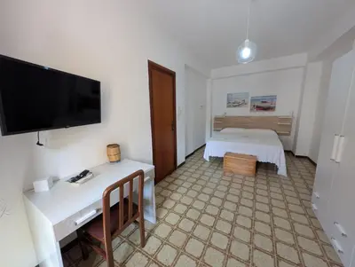 a hotel room with a bed and a desk with a television at Terrazza al mare in Santa Flavia
