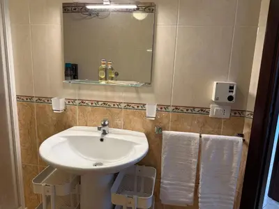 a bathroom with a sink and a mirror and towels at Carol's Sicily Dream in San Vito lo Capo